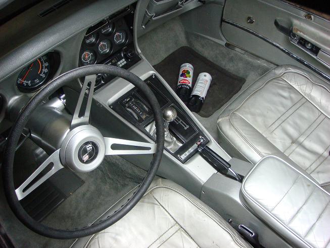 Corvette interior with black steering wheel, manual shifter, and white leather seats