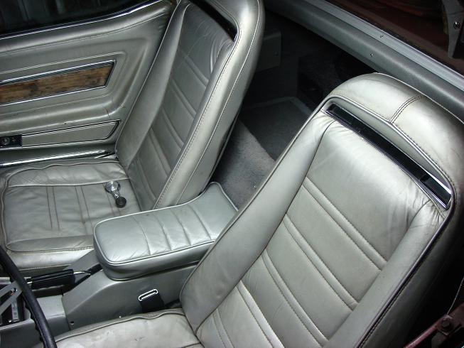 Worn silver leather bucket seats and center console armrest inside a 1975 Chevrolet Corvette