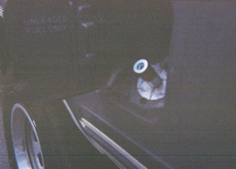 1991 Ford Bronco - Close-up of a dark vehicle's fuel filler door, indicating it requires unleaded fuel.
