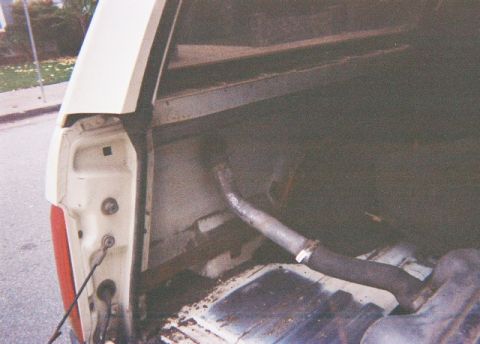 1991 Ford Bronco - The rear cargo area of a vehicle is shown, with a section of exhaust pipe running through it.