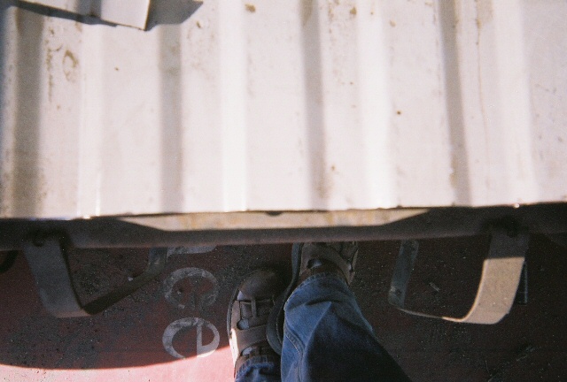 Underside of a white vehicle with visible metal brackets and red painted floor with white lettering