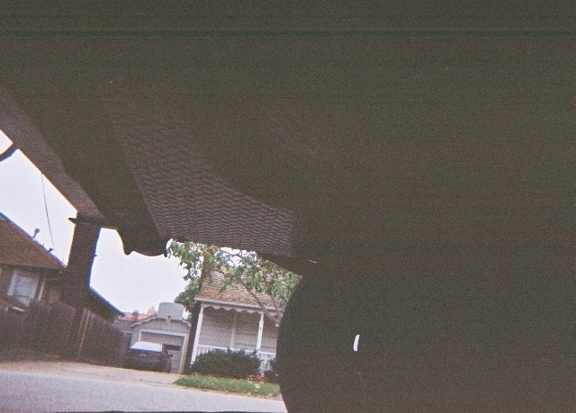Interior view of a car looking out at houses and a street with another vehicle