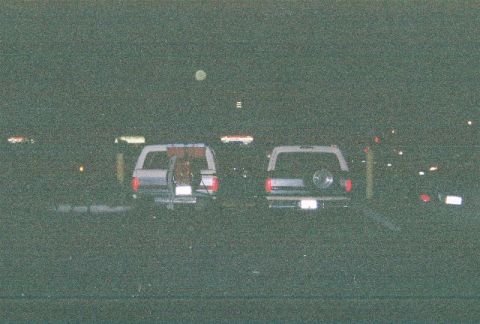 1991 Ford Bronco - Two 1991 Ford Broncos are parked at night. The Bronco on the left has a bike rack on its rear.