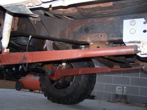 1979 Ford Bronco - The underside of a vehicle reveals its suspension and drivetrain components.