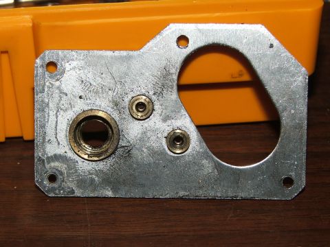 1996 Ford Bronco - A metal bracket with various holes and brass fittings is shown against a blurred orange background.