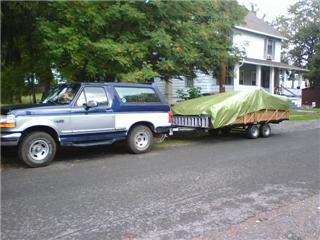 1995 Ford Bronco - A 1995 Ford Bronco is seen from the side, towing a trailer covered by a green tarp.