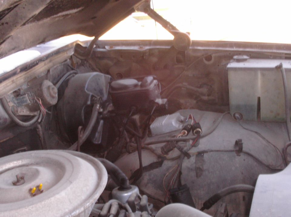 Engine bay with brake master cylinder, air cleaner housing, and wiring. Dusty and aged components