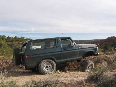 1979 Ford Bronco - This Ford Bronco is navigating a rough, off-road trail with a scenic desert landscape in the background.