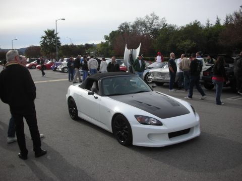 1998 Ford Crown Victoria - white Honda S2000 roadster with a black soft top and dark wheels parked among other cars at an outdoor show.
