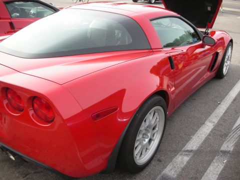 1998 Ford Crown Victoria - red Corvette Z06 coupe shown from the rear three-quarter with quad taillights and silver wheels in a parking lot.