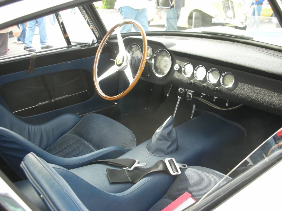 Blue-trimmed interior of a vintage Ferrari with wood-rim steering wheel