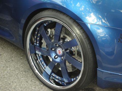1998 Ford Crown Victoria - Detail of a blue sports car's polished-lip blue HRE wheel with low-profile tire and visible brake caliper.