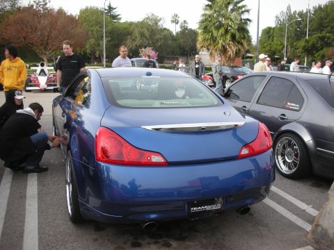 1998 Ford Crown Victoria - Rear three-quarter view of a blue coupe with chrome trunk trim and dual exhaust, surrounded by spectators at an outdoor car meet.