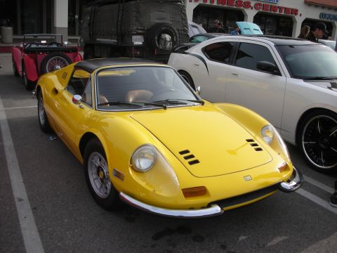 1998 Ford Crown Victoria - Front three-quarter view of a yellow Ferrari Dino targa with chrome bumpers and alloy wheels, parked among other show cars.