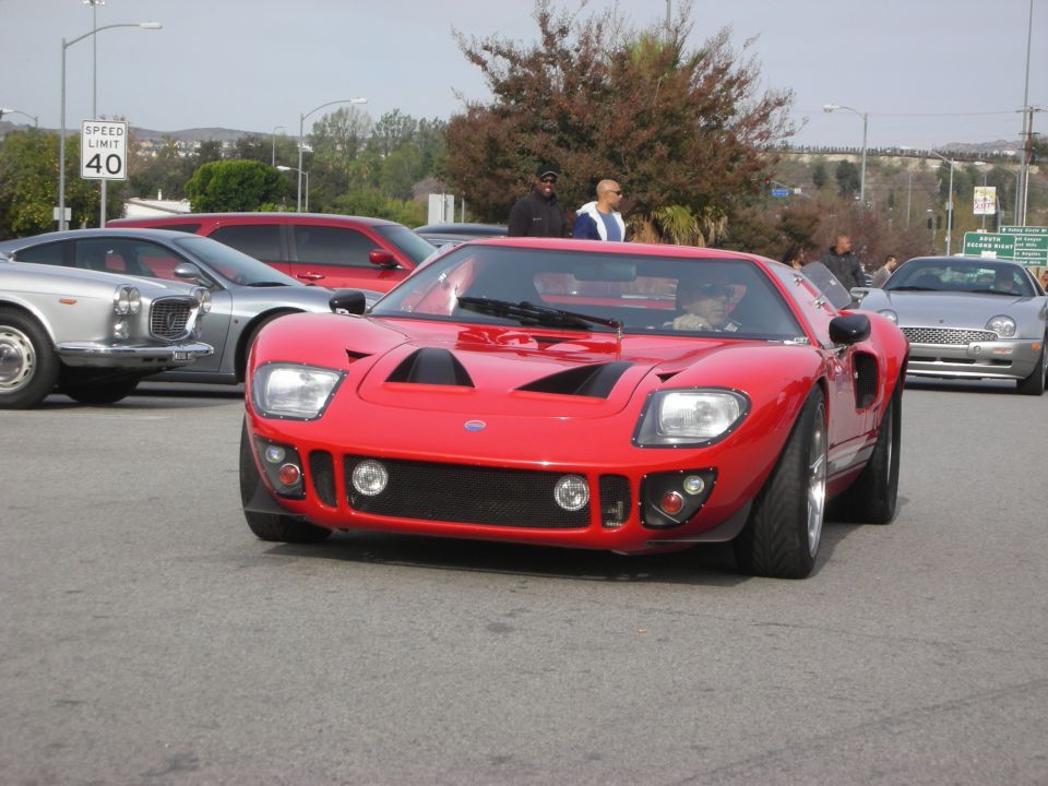 Red Ford GT40-style sports car driving on a street near a 40 mph sign