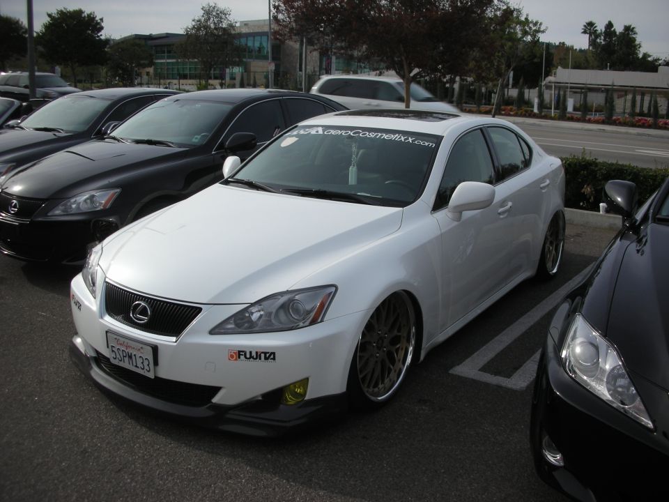 White Lexus IS sedan lowered on bronze mesh wheels in a parking lot