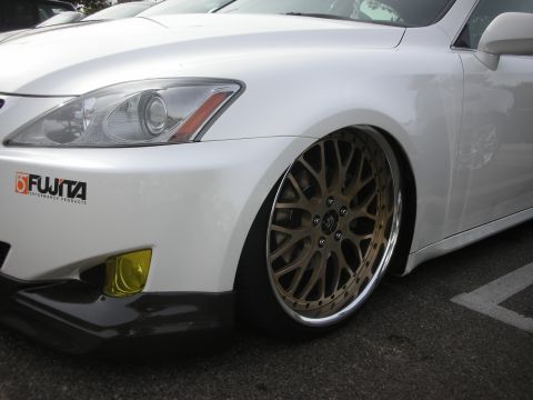1998 Ford Crown Victoria - Close-up of a white lowered Lexus IS front fender and bronze mesh wheel with a Fujita decal and yellow fog light.