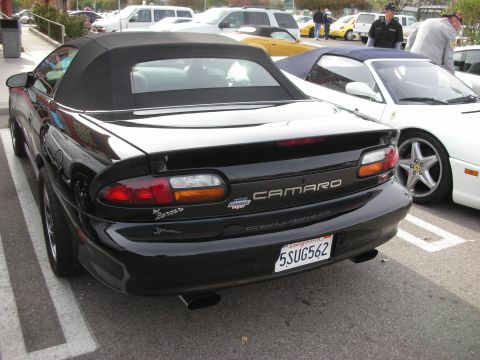 1998 Ford Crown Victoria - Rear of a black Chevrolet Camaro convertible showing badges and a California license plate, parked beside other cars.