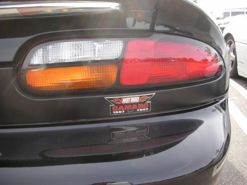 1998 Ford Crown Victoria - Close-up of a black Camaro's rear tail light area bearing a Hot Rod Camaro 1967-2002 anniversary sticker.