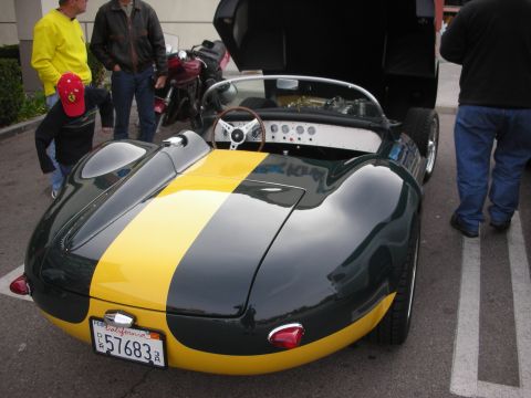 1998 Ford Crown Victoria - British racing green roadster with a yellow racing stripe shown from the rear, with a California plate and onlookers nearby.