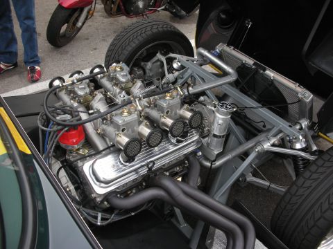 1998 Ford Crown Victoria - Engine bay of a vintage sports car showing a polished inline engine fed by triple side-draft carburetors in a tubular frame.
