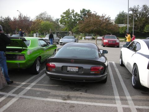 1998 Ford Crown Victoria - Rear three-quarter view of a dark gray Dodge Viper coupe parked at a car meet, with a green muscle car nearby.