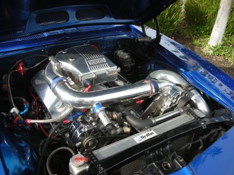 1998 Ford Crown Victoria - Engine bay of a blue muscle car fitted with a Vortech supercharger and polished intake piping.