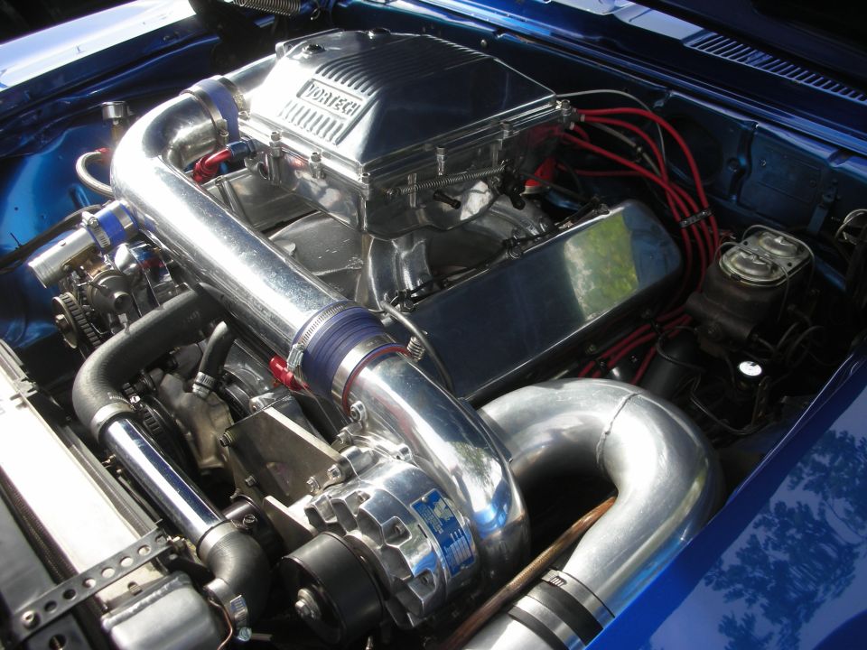 Polished ProCharger-supercharged V8 engine in a blue car engine bay