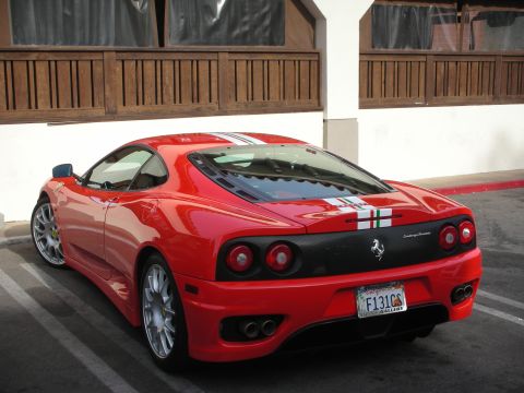 1998 Ford Crown Victoria - Rear three-quarter view of a red Ferrari 360 Challenge Stradale with an Italian tricolor stripe, parked by a wooden building.