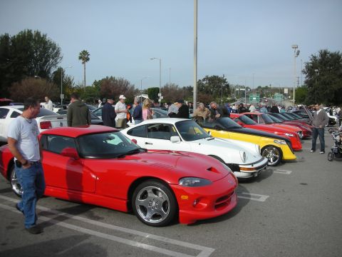 1998 Ford Crown Victoria - line of parked sports cars headed by a red Dodge Viper, with a white Viper and yellow car behind, at an outdoor meet.