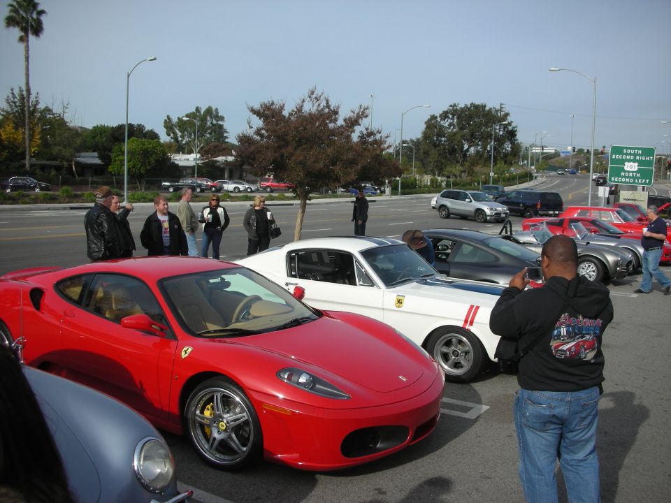 Red Ferrari F430 coupe in parking lot with people and other sports cars