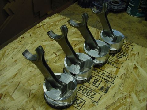 1979 Ford Bronco - Engine pistons and connecting rods laid out on a workbench, possibly for rebuild or inspection.
