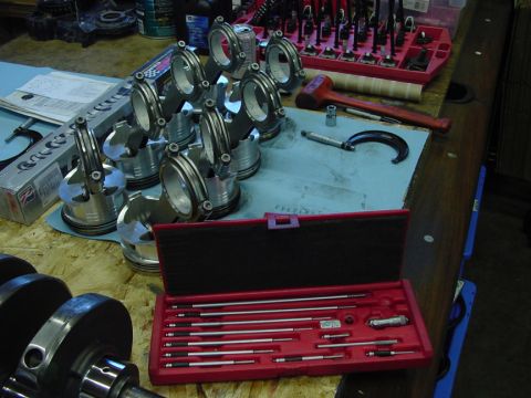 1979 Ford Bronco - Engine components including pistons, connecting rods, and a crankshaft are laid out with various precision measuring tools.