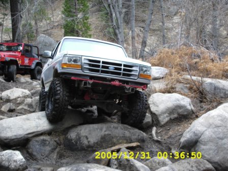 1996 Ford Bronco - White Ford Bronco navigates a rocky trail with a red Jeep following behind.
