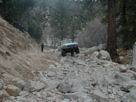 1996 Ford Bronco - Ford Bronco tackles a challenging rocky off-road path in a wooded mountain area.