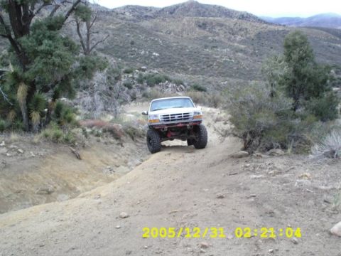 1996 Ford Bronco - A white 1996 Ford Bronco navigates a steep dirt trail in a mountainous, arid landscape.