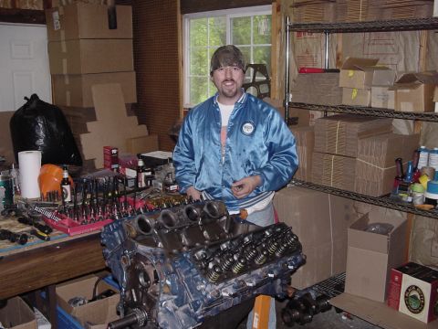 1979 Ford Bronco - Man in a workshop with an engine block and various tools laid out on a workbench.