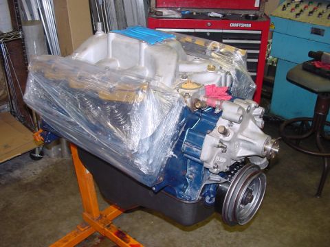1979 Ford Bronco - Engine assembly covered in plastic wrap sits on an orange stand in a workshop.