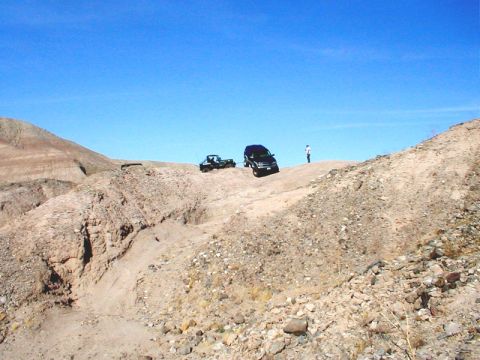 1996 Ford Bronco - Two vehicles navigate a , dry landscape under a bright blue sky.