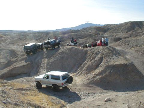1996 Ford Bronco - Several SUVs navigate a off-road course under a clear sky.