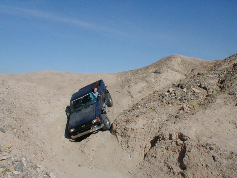 Blue SUV driving down a steep, sandy hill with a person in the driver's seat