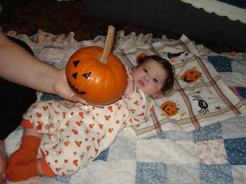 2000 Ford Crown Victoria - A baby lies on a quilt with a carved pumpkin nearby, dressed in a festive onesie.