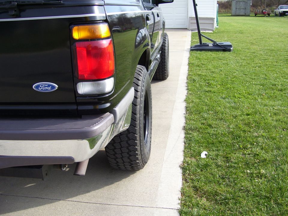 Black Ford Explorer rear quarter panel, chrome bumper, and off-road tire