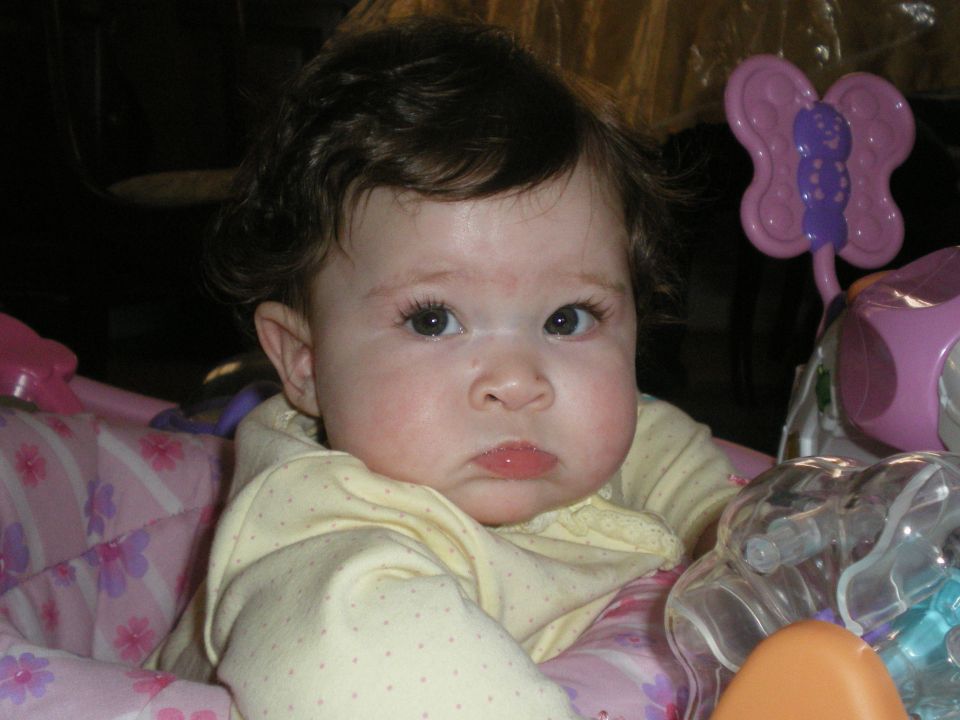 Baby in a pink and yellow patterned seat with toys
