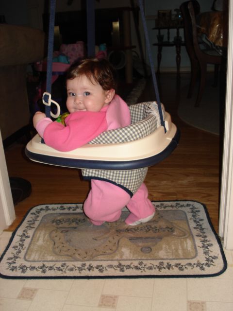 2000 Ford Crown Victoria - A baby smiles while sitting in a jumper seat, suspended by blue straps.