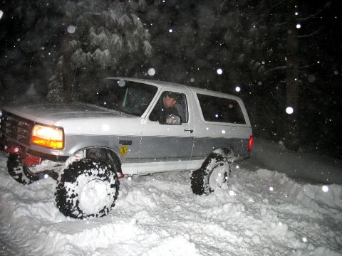 1996 Ford Bronco - A 1996 Ford Bronco navigates a snowy trail during a winter night, with snow falling around it.
