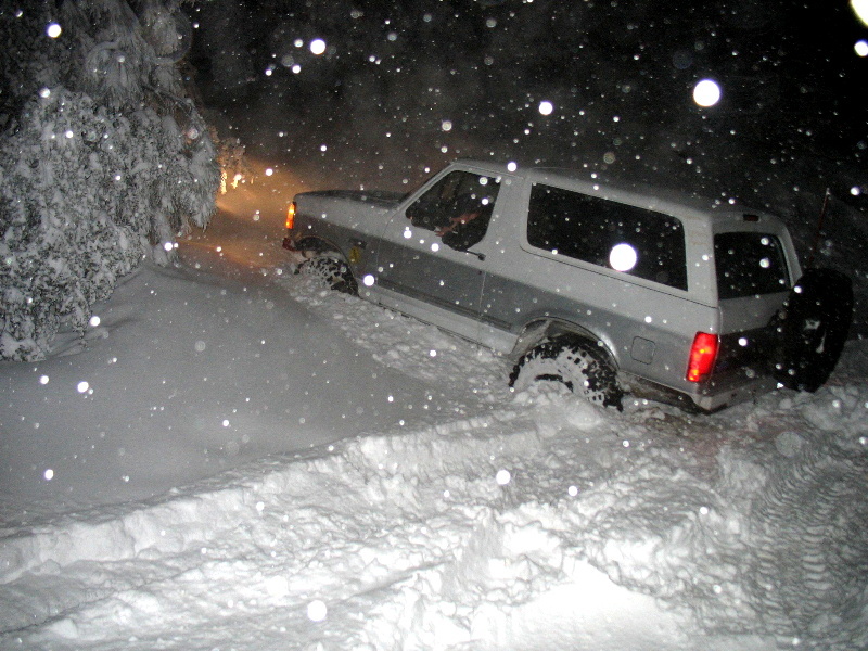 1996 Ford Bronco driving through deep snow at night