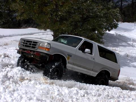 1996 Ford Bronco - Silver 1990s Ford Bronco full-size two-door SUV with a suspension lift and large off-road tires, plowing through deep snow. The truck is sh…
