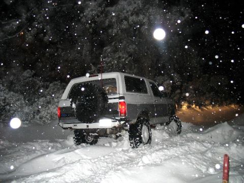 1996 Ford Bronco - Ford Bronco navigates a snow-covered road during a snowfall at night.