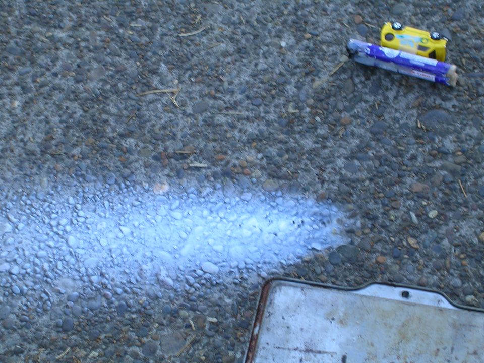 Yellow toy car on a purple and white firework tube on asphalt